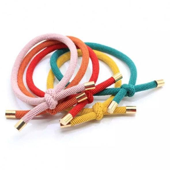 Colorful hair ties with gold ends on a white background