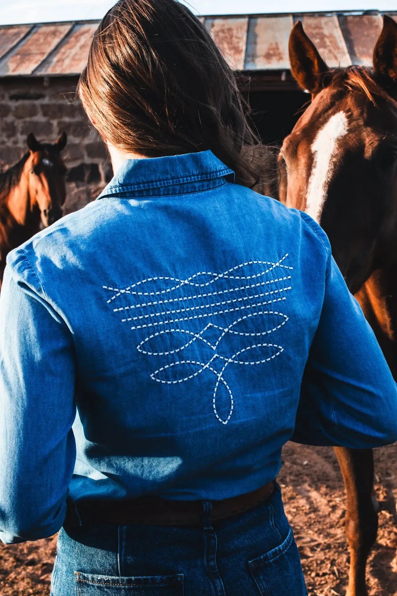 Denim button down with embroidered boot stitch.

True to size with a feminine fit.
65% Cotton, 35% Tencel
Boot stitch embroidery on collar and back.
Pearl snap buttons.