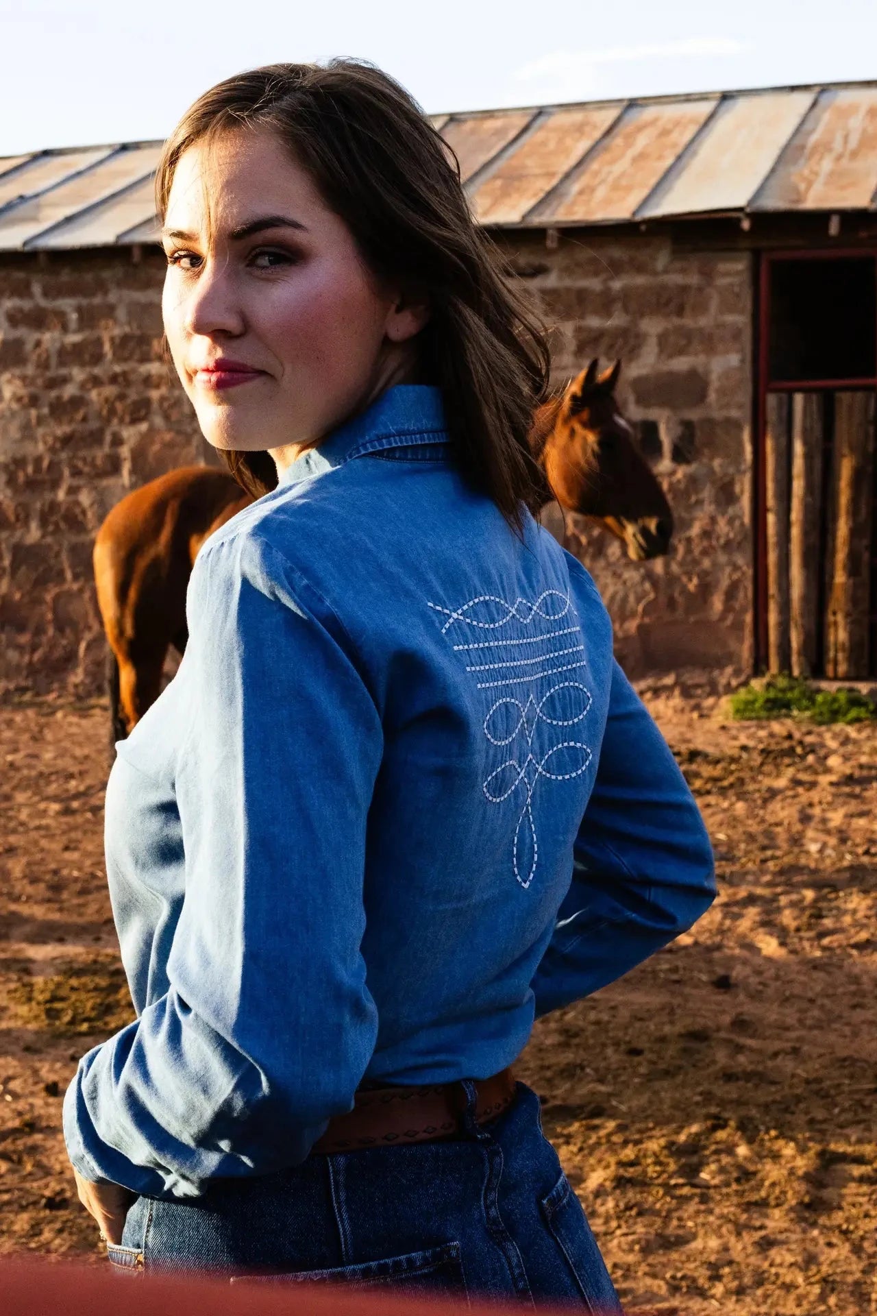 Denim button down with embroidered boot stitch.

True to size with a feminine fit.
65% Cotton, 35% Tencel
Boot stitch embroidery on collar and back.
Pearl snap buttons.