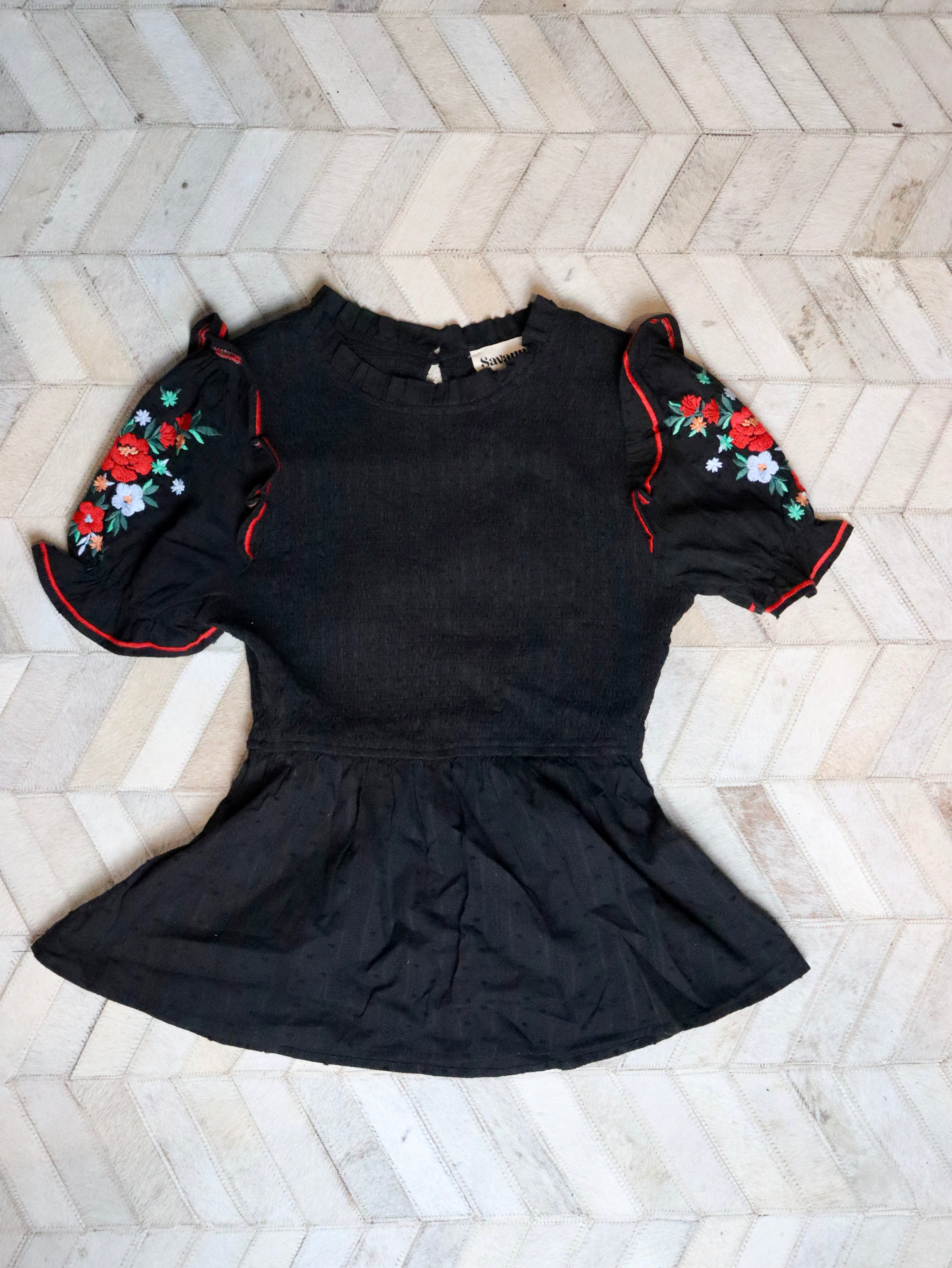 This black smocked embroidered top pairs well with white denim. 
Floral embroidered short puffy sleeves with a smocked bodice.
100% Cotton
Made by Savanna Jane
Small (0-2)
Medium (4-6)
Large (8-10)