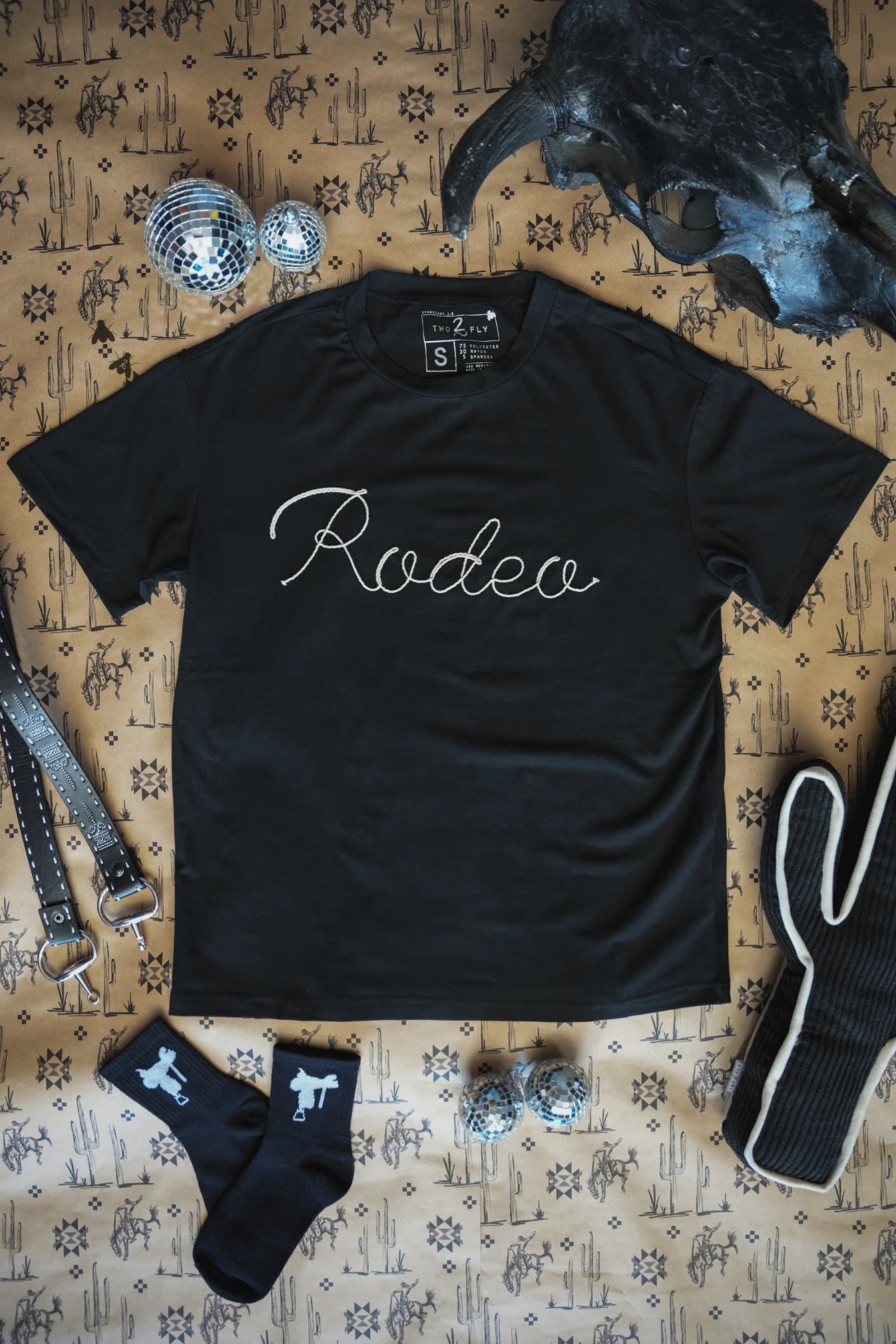 Black t-shirt with rodeo in rope embroidery. &nbsp;

3D rope embroidery:)
75% Polyester, 20% Rayon, 5% Spandex
True to size.
Made by 2 FLY