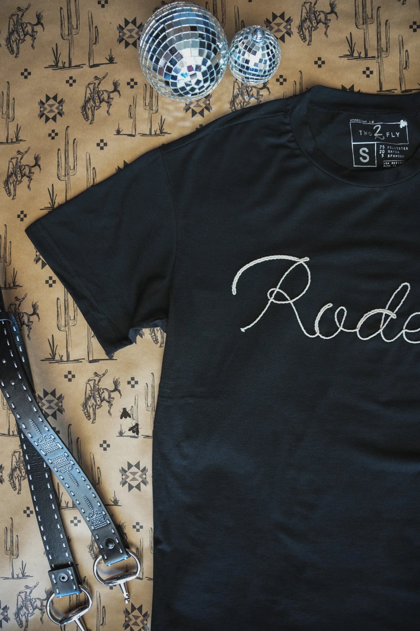 Black t-shirt with rodeo in rope embroidery. &nbsp;

3D rope embroidery:)
75% Polyester, 20% Rayon, 5% Spandex
True to size.
Made by 2 FLY