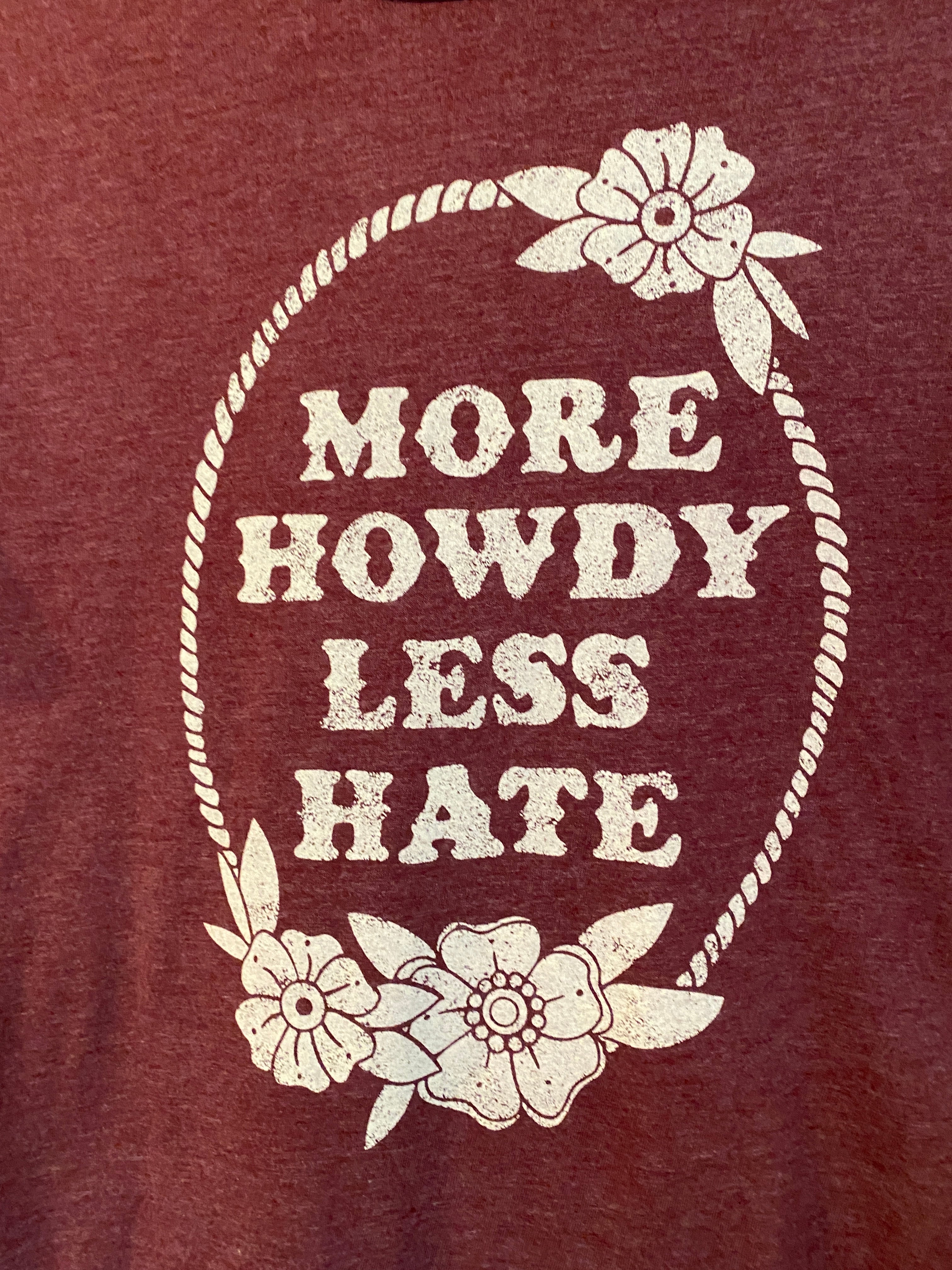 More Howdy Less Hate tee features a unisex fit in maroon with cream screen printed art.   Made by Ali-Dee Gig 'Em